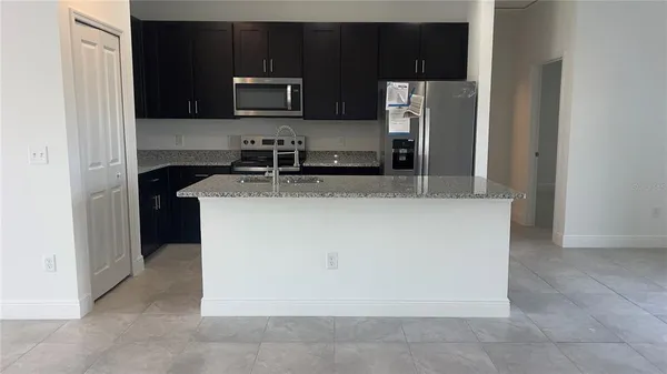 a kitchen with stainless steel appliances granite countertop a refrigerator a stove a sink and a microwave