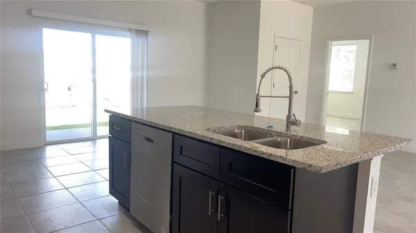 a kitchen with a granite countertop sink a window and cabinets