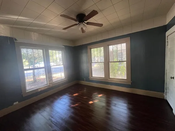 a view of an empty room with wooden floor and a window