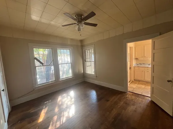 a view of an empty room with wooden floor and a window