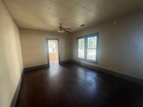 an empty room with wooden floor and windows