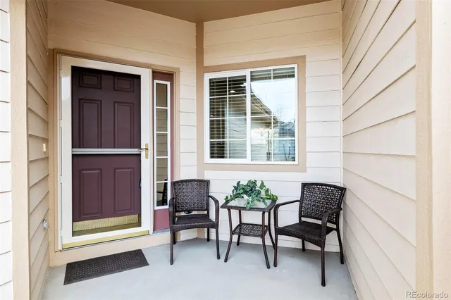 a porch with a chair and a potted plant next to a window