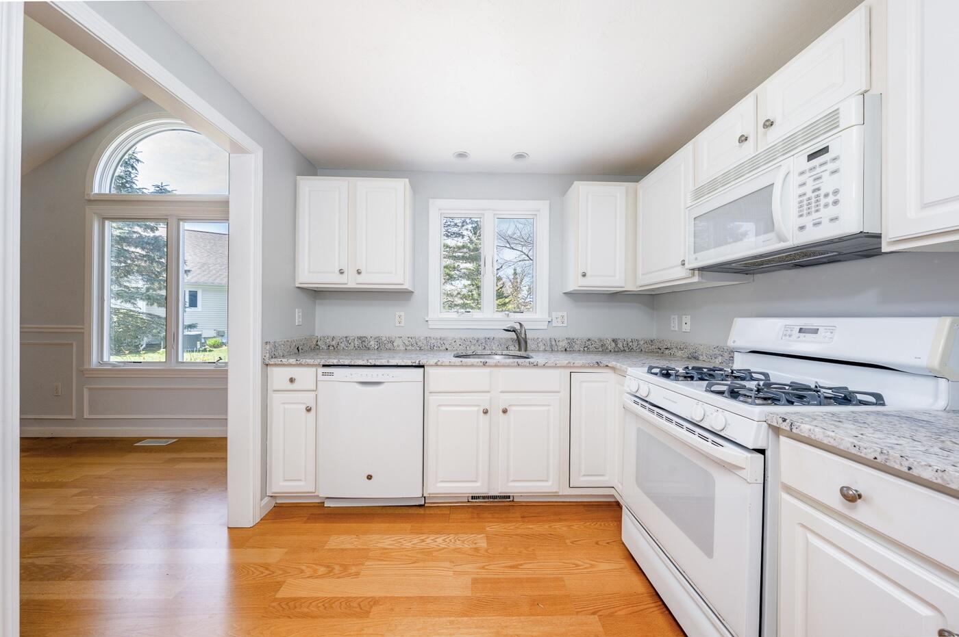 15 Beacon Court Mashpee, MA 02649 - Photo 4 of 33 a kitchen with stainless steel appliances granite countertop a stove a sink and white cabinets with wooden floor
