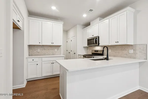 a kitchen with granite countertop white cabinets white stainless steel appliances and a sink