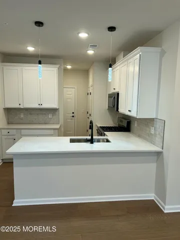 a kitchen with kitchen island sink and white cabinets