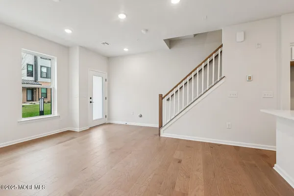 a view of an empty room with wooden floor and stairs