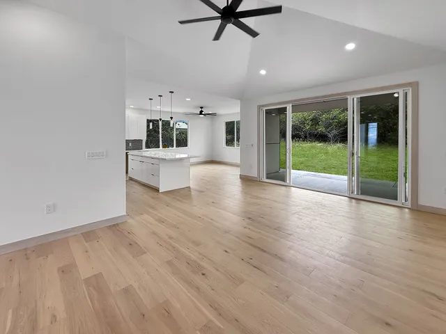 a view of open kitchen with wooden floor and a ceiling fan
