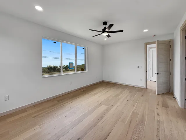 a view of empty room with wooden floor and fan