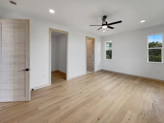 a view of empty room with wooden floor and fan