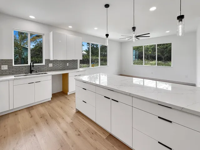 a large kitchen with kitchen island a large window cabinets and stainless steel appliances