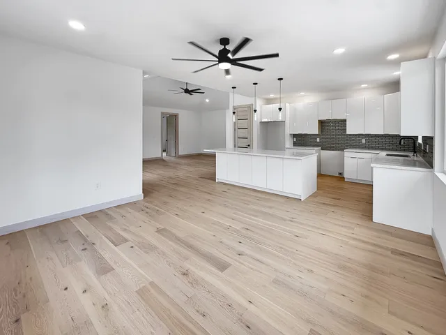 a living room with stainless steel appliances furniture wooden floor and a view of kitchen