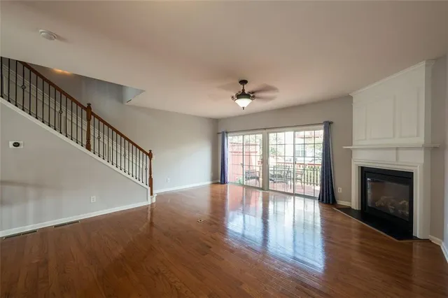 a view of an empty room with wooden floor fireplace and a window