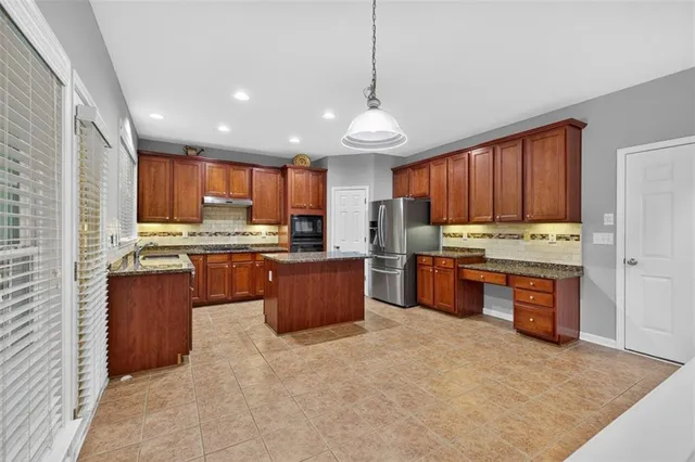 a kitchen with stainless steel appliances granite countertop a stove a sink dishwasher a refrigerator and a oven with wooden floor