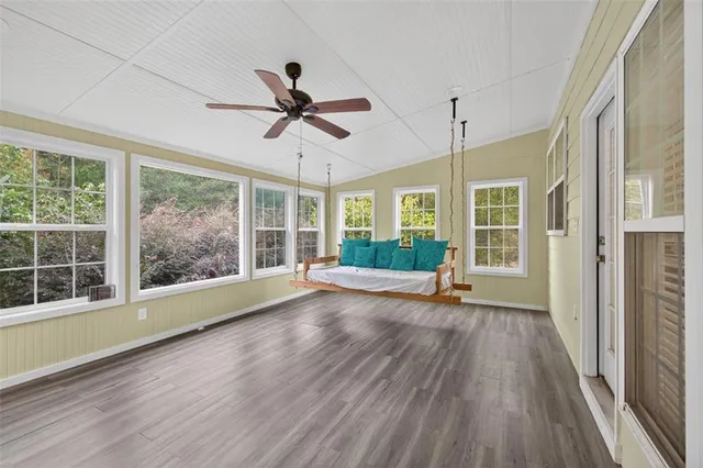 a view of a livingroom with wooden floor a fireplace a ceiling fan and window