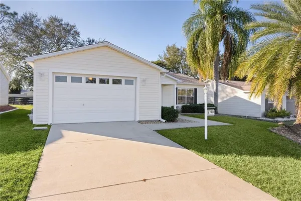 a view of a house with a yard and palm trees