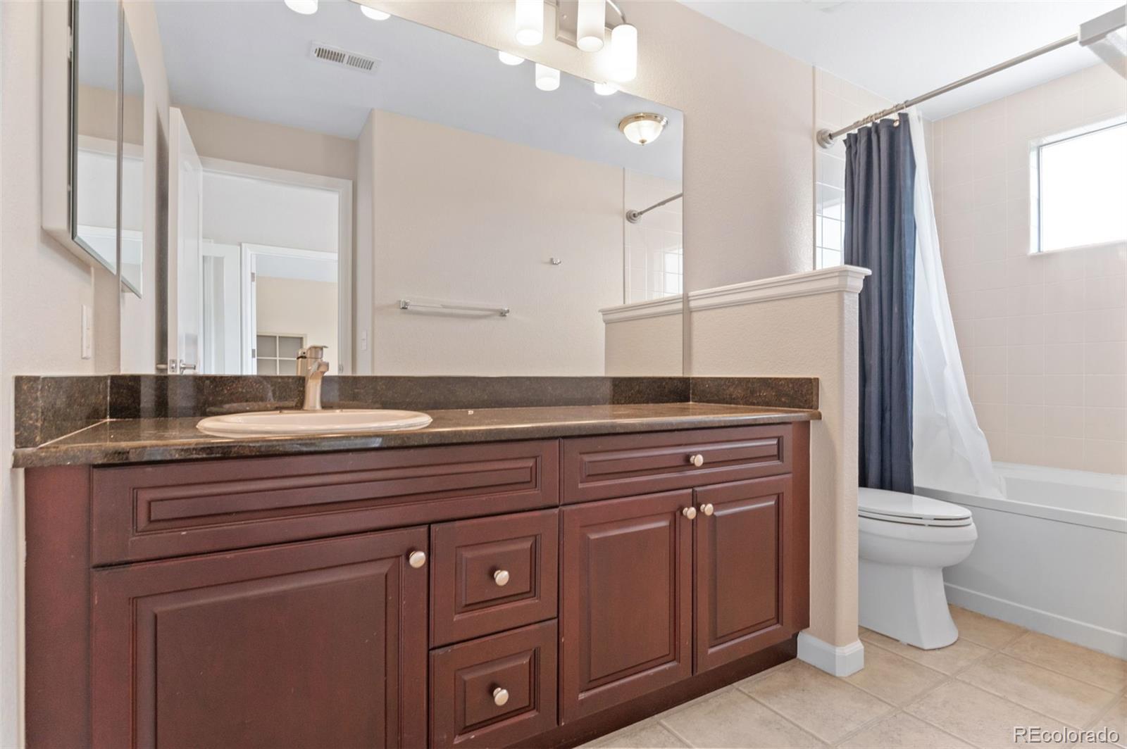 8540 Gold Peak Lane, Unit C Highlands Ranch, CO 80130 - Photo 26 of 37 a spacious bathroom with a granite countertop toilet sink and mirror