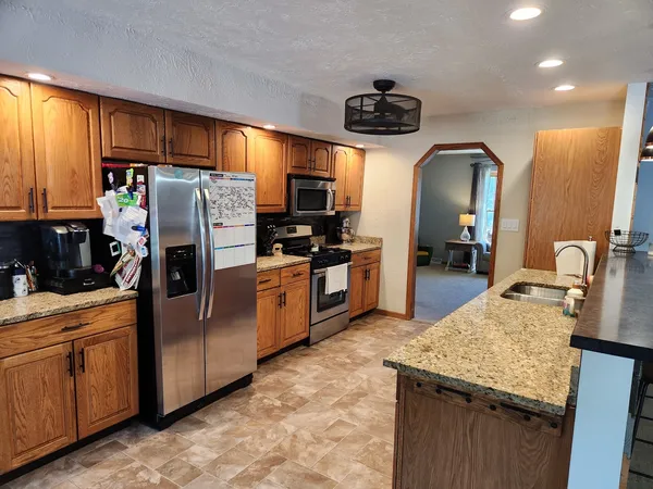 a kitchen with stainless steel appliances granite countertop a refrigerator a stove and a sink