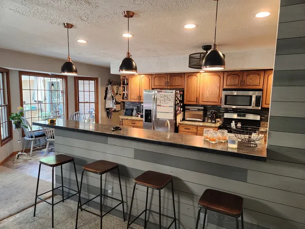 a kitchen with stainless steel appliances a dining table chairs and a refrigerator