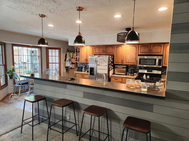 a kitchen with stainless steel appliances a dining table chairs and a refrigerator