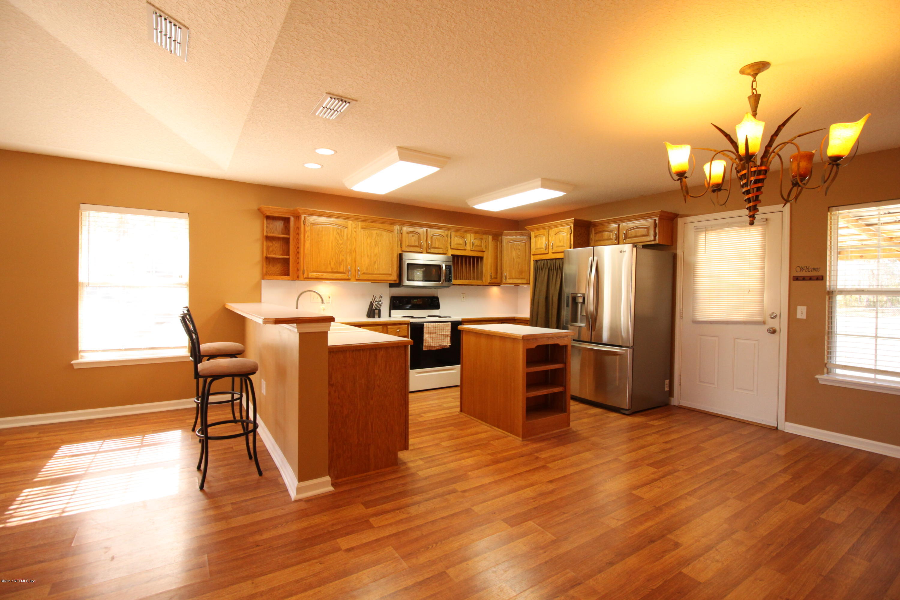 54303 Cravey Road Callahan, FL 32011 - Photo 5 of 13 a living room with stainless steel appliances kitchen island granite countertop a table chairs and a refrigerator