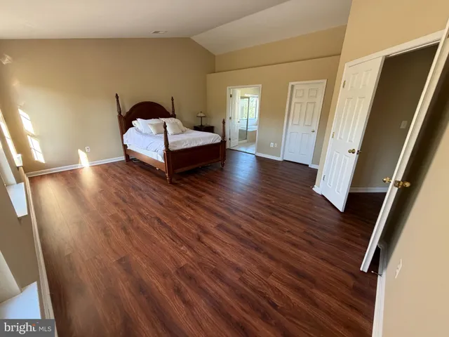 a view of an empty room with wooden floor and window