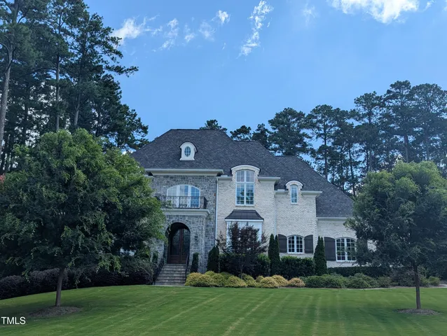a front view of a house with a garden and trees