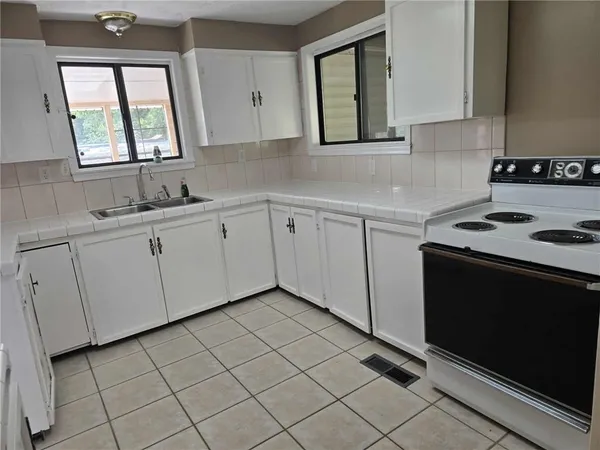 a kitchen with white cabinets a sink and a stove