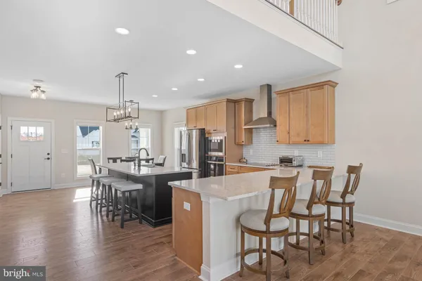 a kitchen with a dining table chairs wooden floor cabinets and stainless steel appliances