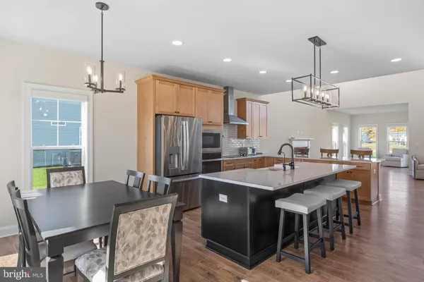 a kitchen with stainless steel appliances kitchen island granite countertop a dining table chairs and white cabinets