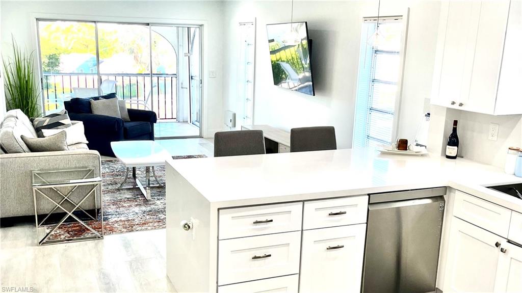 53 High Point Circle West, Unit 304 Naples, FL 34103 - Photo 2 of 11 a kitchen with a white cabinets and chairs