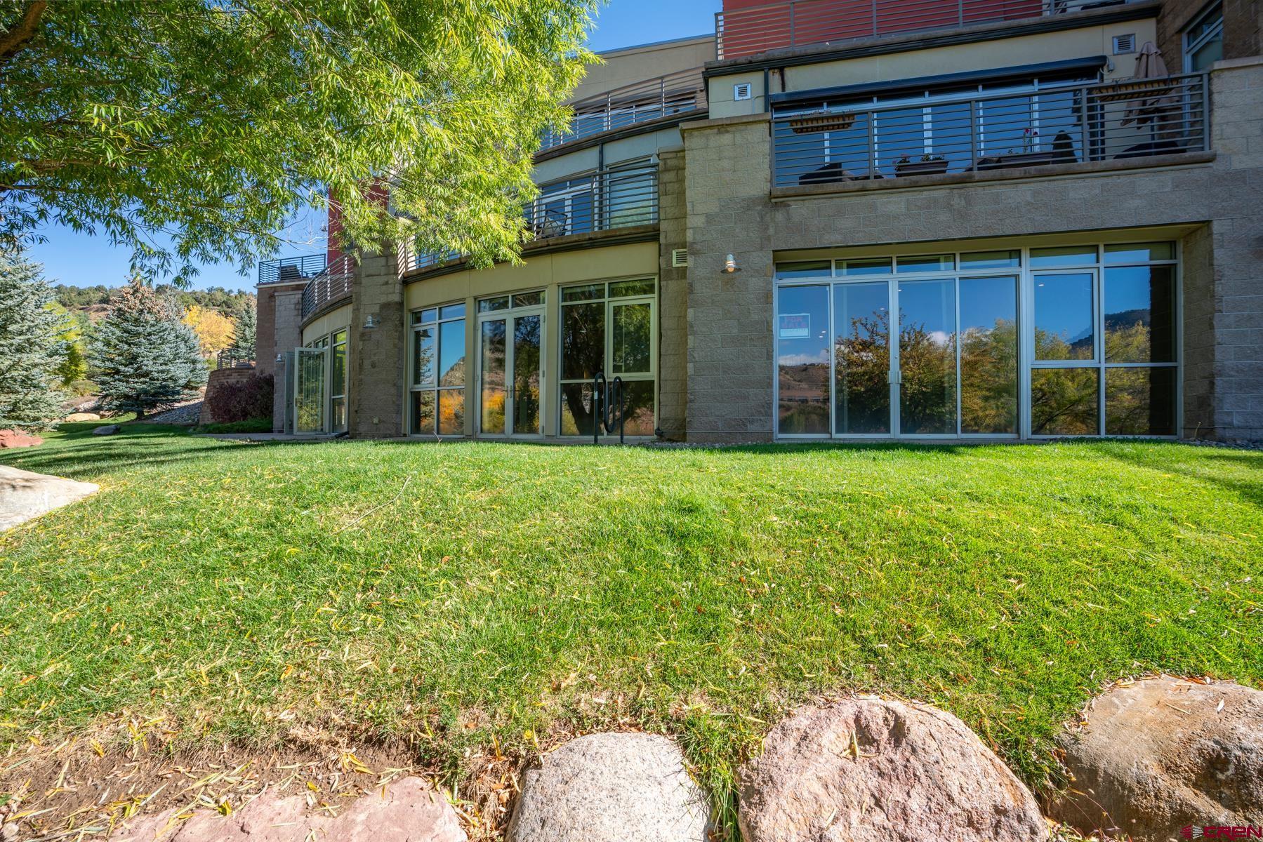 555 Rivergate Lane, Unit B482 Durango, CO 81301 - Photo 3 of 35 a view of a brick house with a big yard and large trees