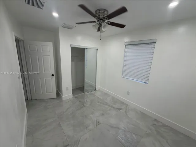 an empty room with a ceiling fan and a window