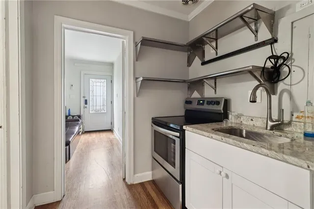 a kitchen with stainless steel appliances granite countertop white cabinets and a wooden floor