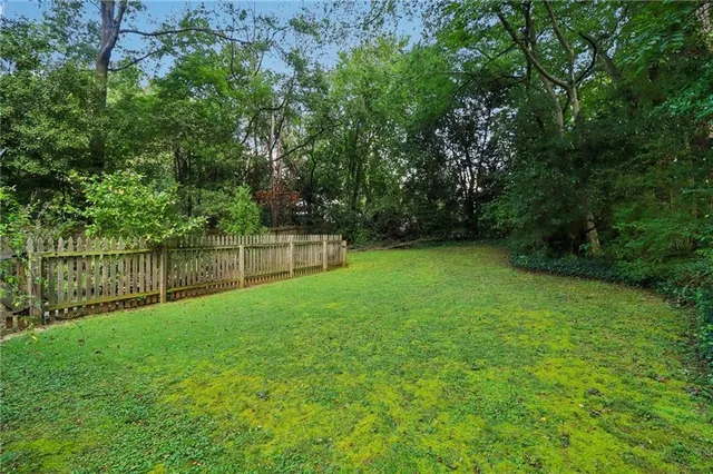 a view of a yard with a fence and trees