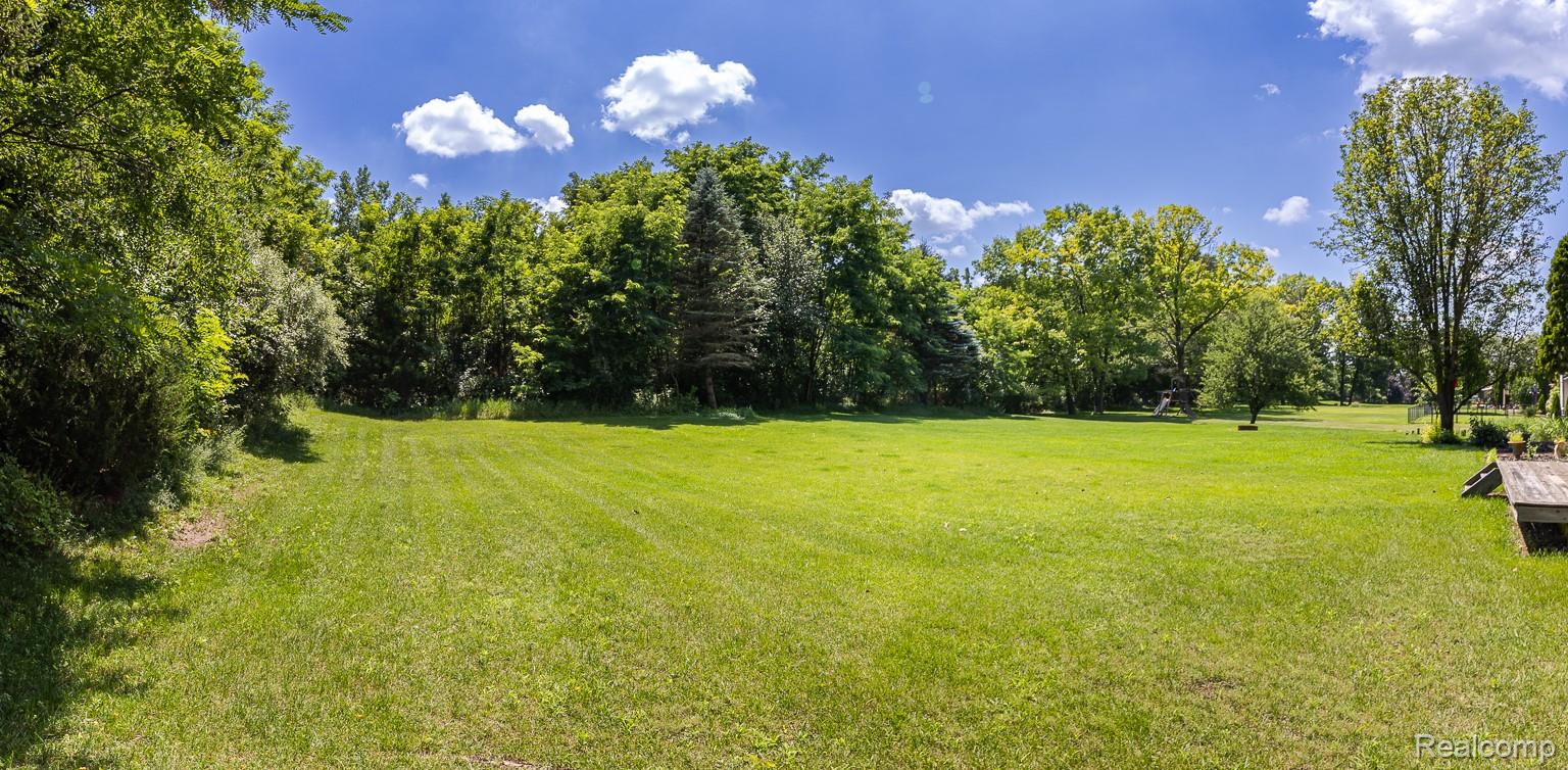 312 Reid Road Highland, MI 48357 - Photo 3 of 5 Expansive green lawn surrounded by mature trees.