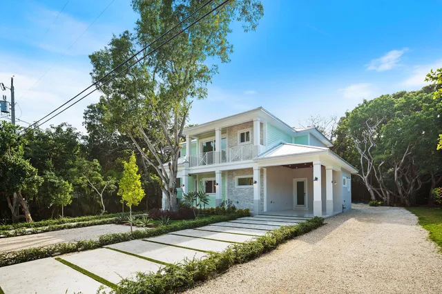 a view of a white house next to a road and yard