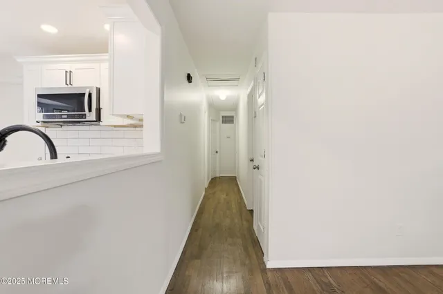 a view of a hallway with wooden floor and a sink