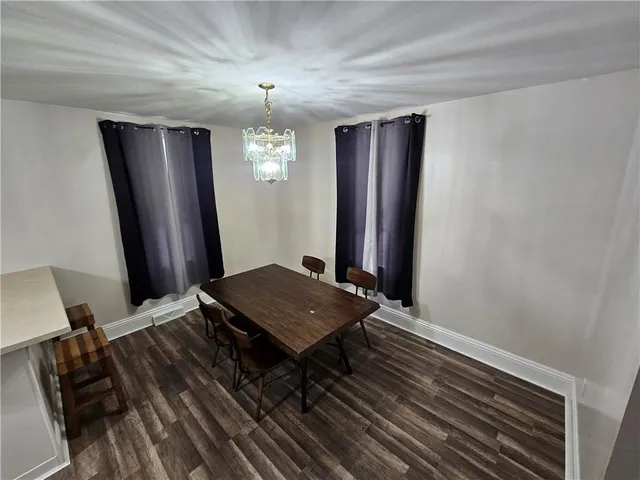 a living room with wooden floor and paintings on the wall