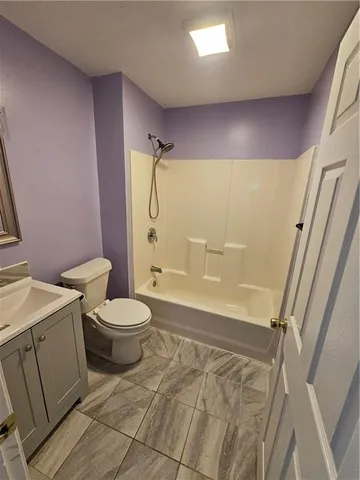 a bathroom with a granite countertop bathtub shower sink vanity and toilet