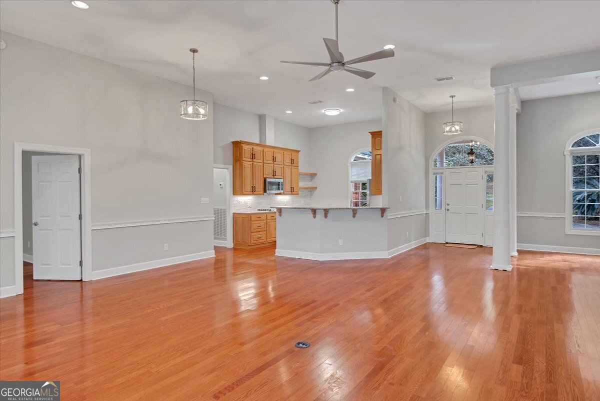 396 Meander Trace Thomasville, GA 31792 - Photo 27 of 50 an empty room with wooden floor and kitchen view