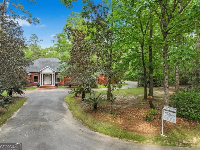 an aerial view of a house with a yard and large trees