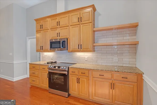 a kitchen with granite countertop white cabinets stainless steel appliances and wooden floor