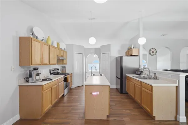 a living room with stainless steel appliances kitchen island granite countertop a sink dishwasher a stove and a refrigerator