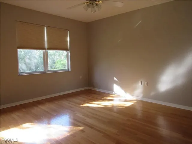 a view of empty room with wooden floor and fan