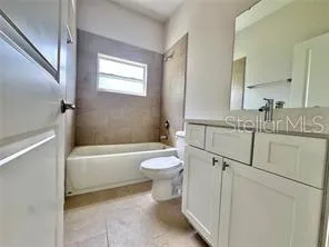 a bathroom with a granite countertop sink toilet a mirror and bathtub