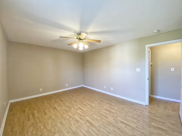 an empty room with wooden floor and fan