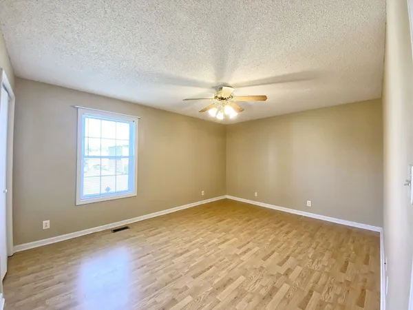 an empty room with wooden floor and chandelier fan