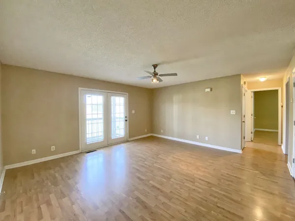 a view of an empty room with glass door and wooden floor