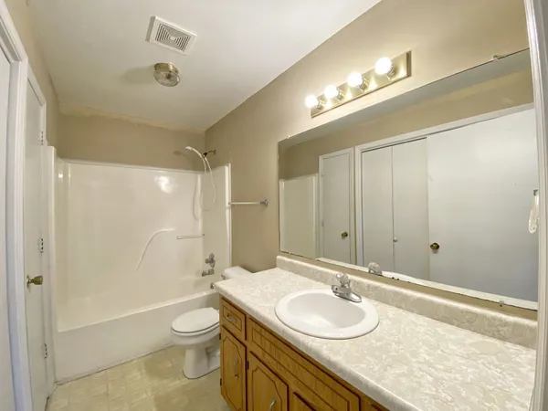 a bathroom with a granite countertop sink a toilet a mirror and shower
