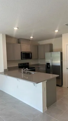 a kitchen with stainless steel appliances a refrigerator a sink a stove a microwave and island